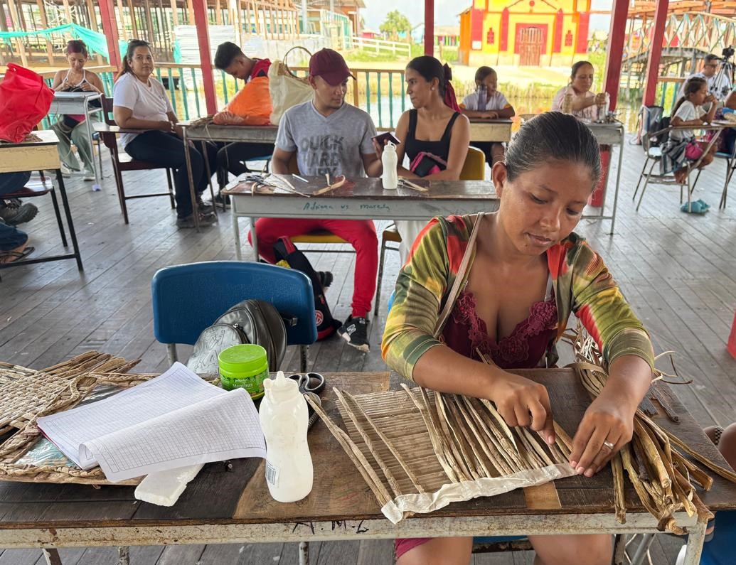 Mujer haciendo artesanias con la taruya sentada en una mesa