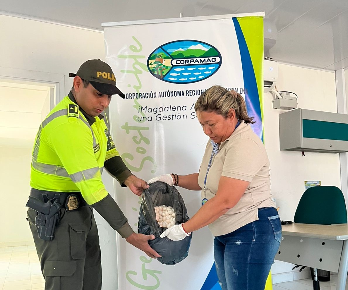 Poliicia y funcionaria sostenien bolsa con huevos de iguana