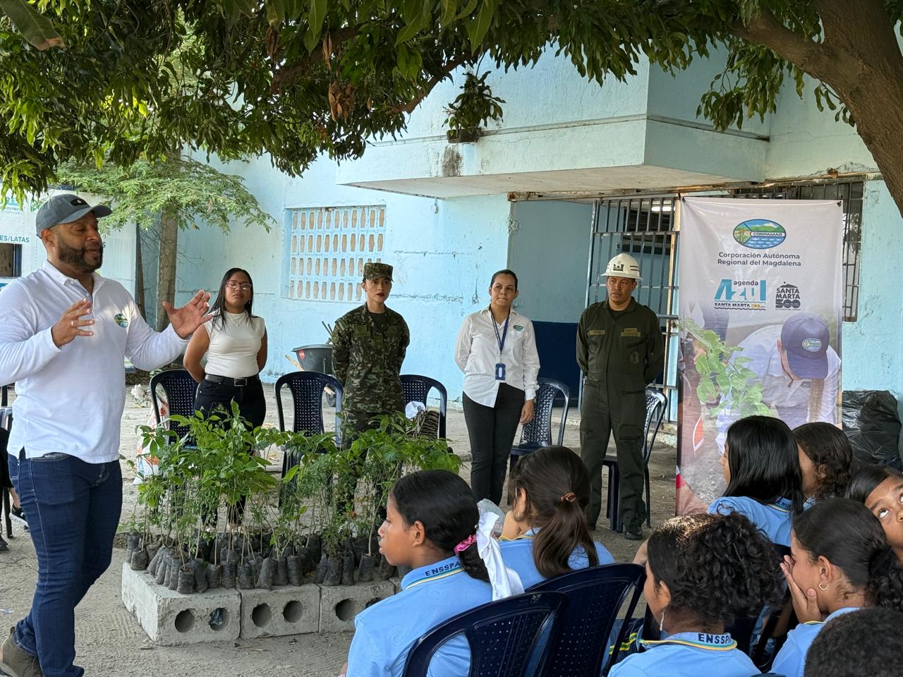 Funcionario dando charla a los niños con arboles en canastas