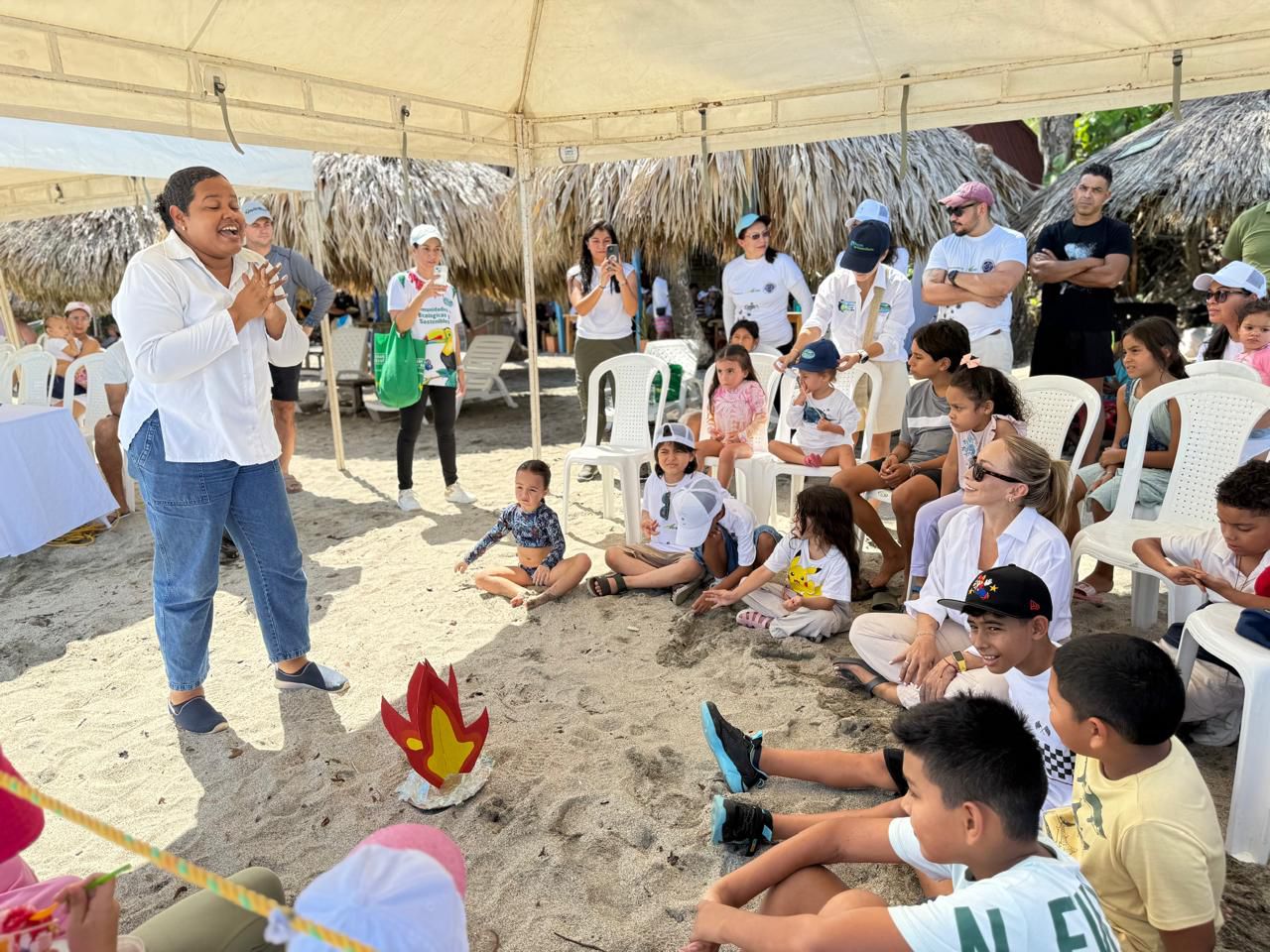 Funcionaria de CORPAMAG dando charla a niños y adultos aire libre en la playa sobre tortugas