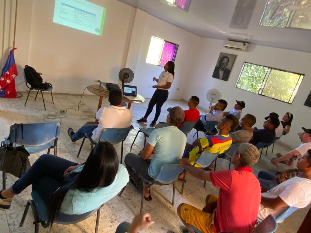 Grupo de personas reunidas en un salòn. Funcionario de Corpamag explicando