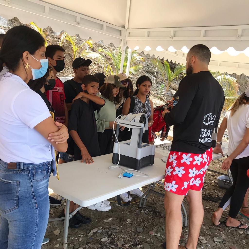 Funcionario de corpamag con estudiantes realizando actividad en la playa de fragmentacion de corales