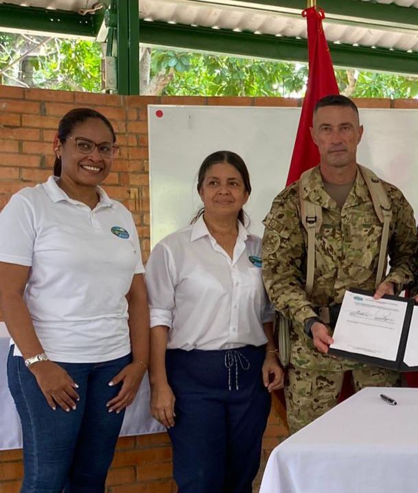 Foto del Brigadier General sosteniendo el documento firmado  y al lado de el funcionaria de CORPAMAG y Jefe de Planeaciòn