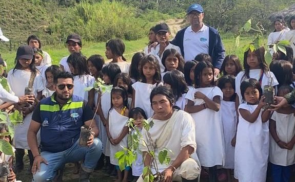 Indigenas y funcionarios en foto grupal con arboles de roble en sus manos