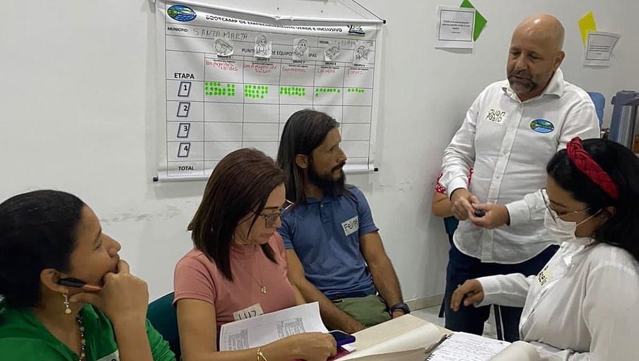 Grupo de trabajo sentados en una mesa con funcionario de CORPAMAG